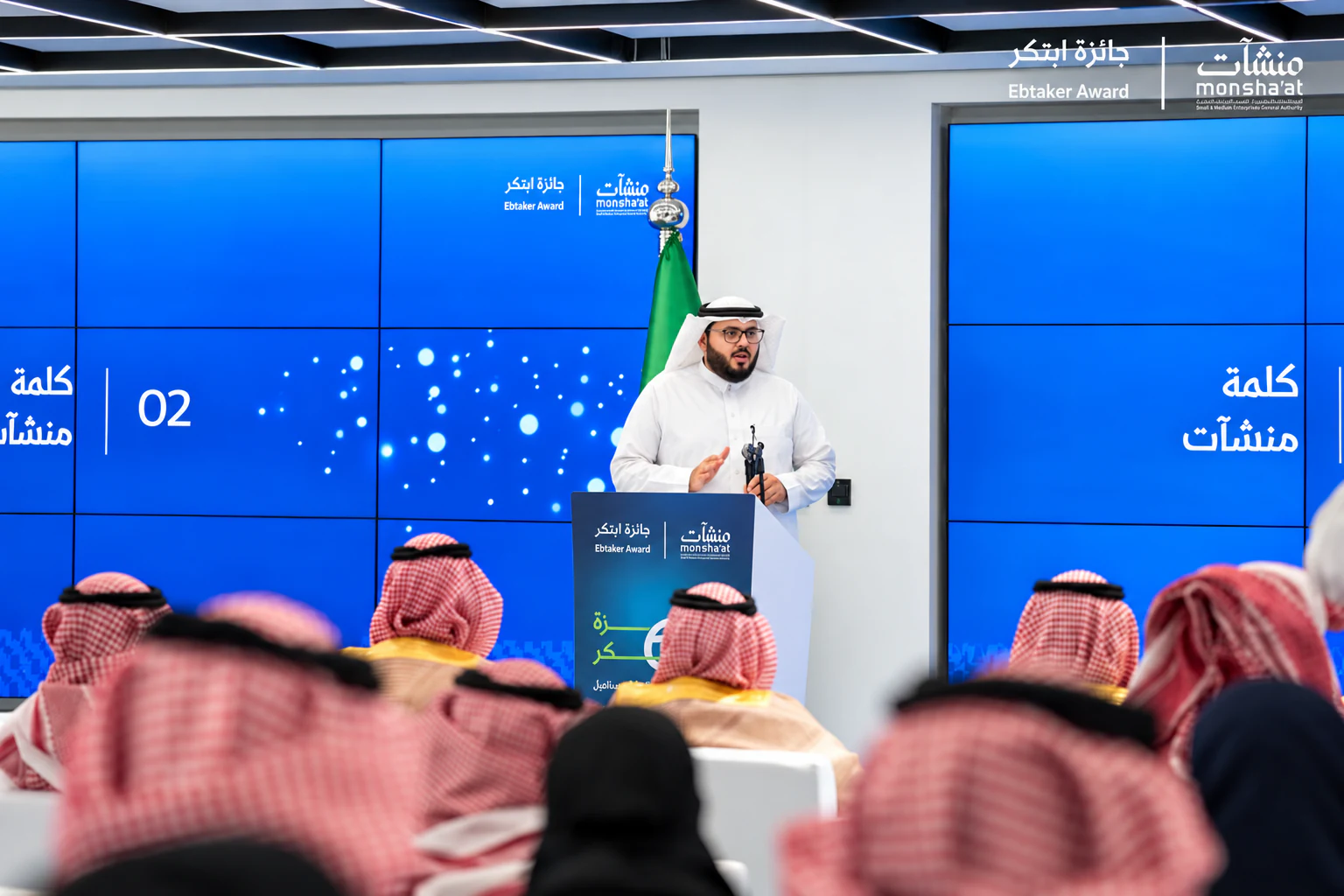 متحدث على منصة حفل جائزة ابتكر والحضور أمامه